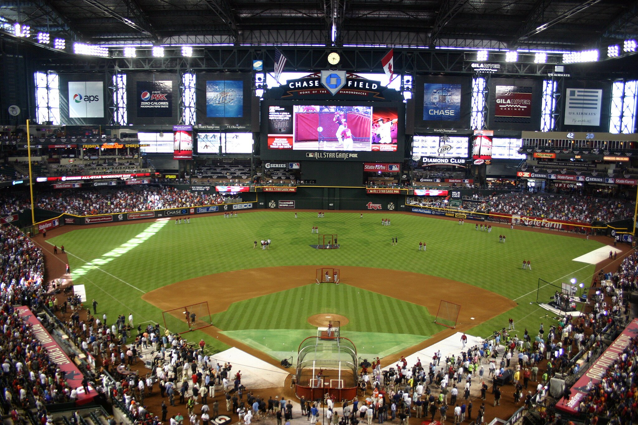 A full interior view of Chase Field during a baseball event, showing a packed crowd, green field, and the main scoreboard.