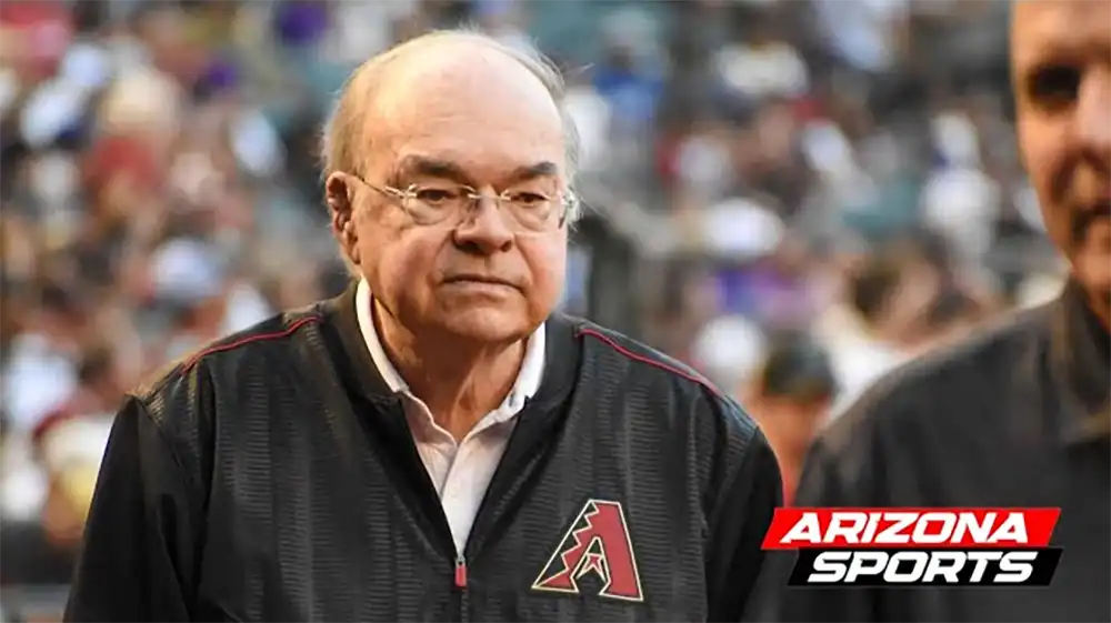 Ken Kendrick – Public Funding Debate at Chase Field Arizona Diamondbacks owner in team gear on the field during a game, with a serious expression and Arizona Sports logo in the corner.